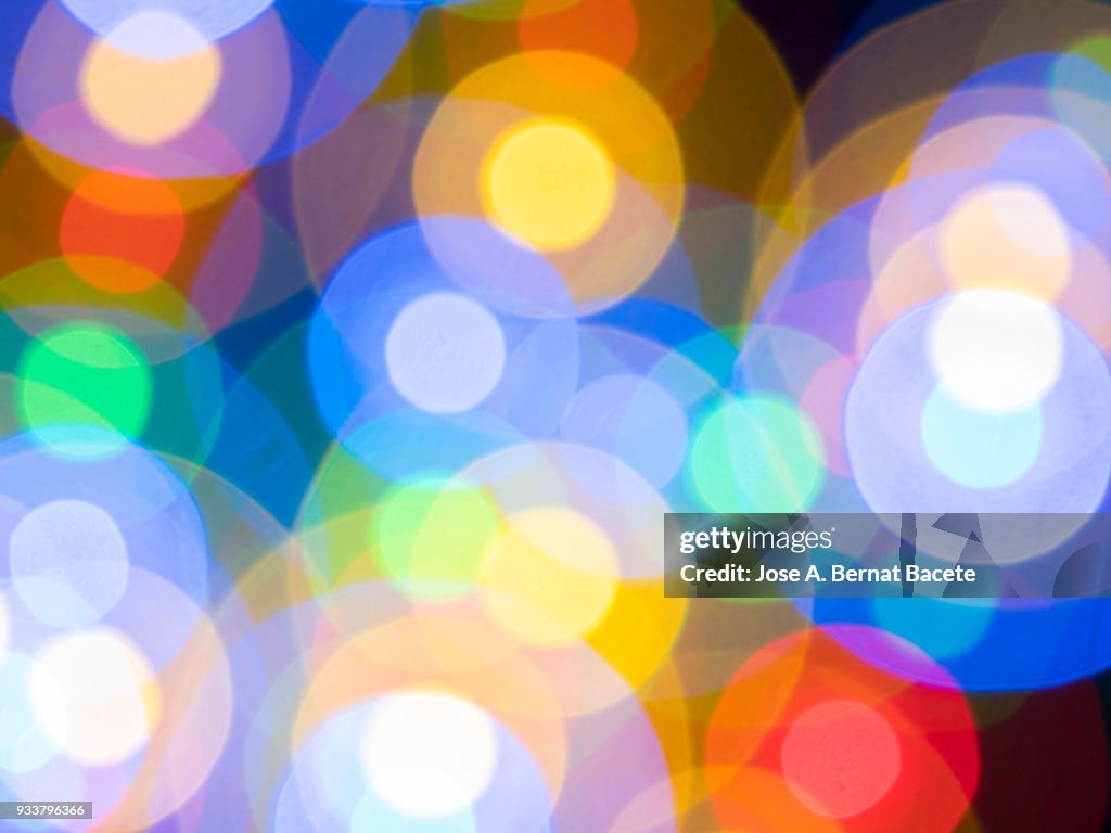 Close-up unfocused of lights of colors in the shape of circles of colors blue, yellow and red on a black background. Spain.