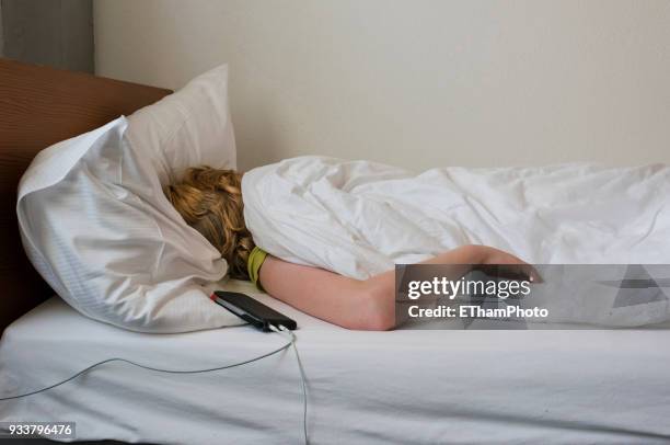 adolescent teenage boy sleeping in his bed next to smartphone - duvet stock pictures, royalty-free photos & images