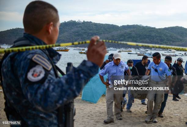 Forensic personnel and police officers carry the body of a murdered man, at Caletilla beach, in the touristic city of Acapulco, Guerrero State,...