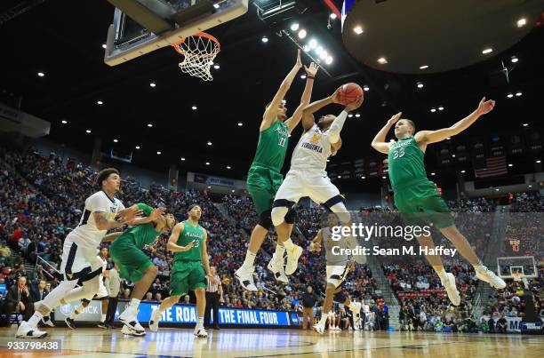 Jevon Carter of the West Virginia Mountaineers shoots against Ajdin Penava and Jon Elmore of the Marshall Thundering Herd in the first half during...