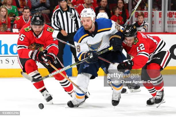 Kyle Brodziak of the St. Louis Blues chases the puck against Artem Anisimov and Alex DeBrincat of the Chicago Blackhawks in the third period at the...