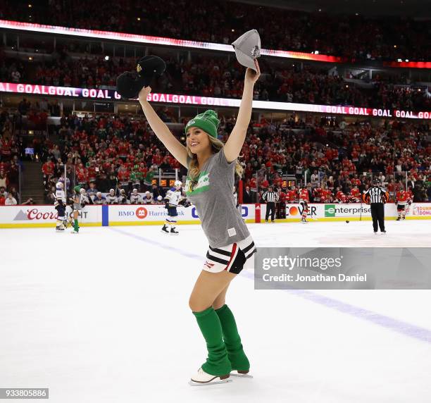 Member of the Chicago Blackhawks "Ice Crew" waves to the crowd holding hats after Alex DeBrincat of the Blackhawks scored a hat trick in the third...