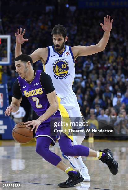 Lonzo Ball of the Los Angeles Lakers drives on Omri Casspi of the Golden State Warriors during an NBA basketball game at ORACLE Arena on March 14,...