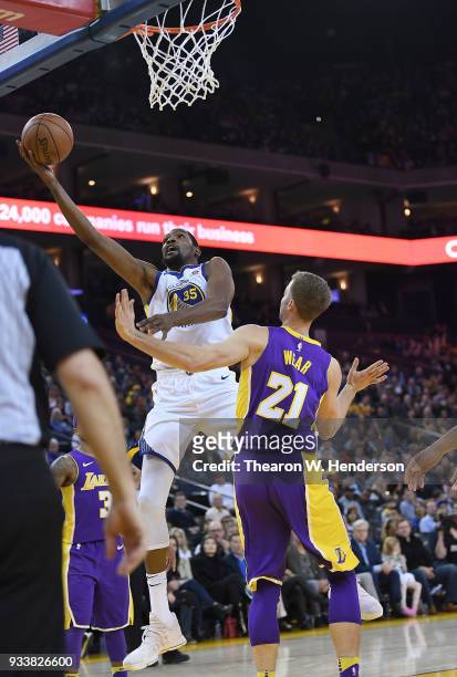 Kevin Durant of the Golden State Warriors goes in for a layup over Travis Wear of the Los Angeles Lakers during an NBA basketball game at ORACLE...