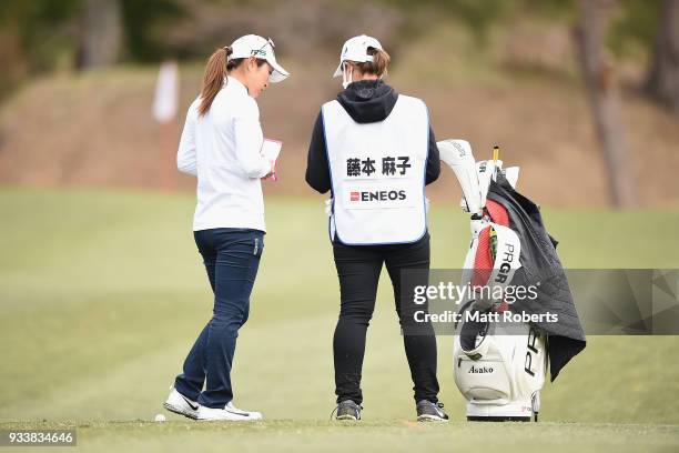 Asako Fujimoto of Japan speaks with her caddie during the final round of the T-Point Ladies Golf Tournament at the Ibaraki Kokusai Golf Club on March...