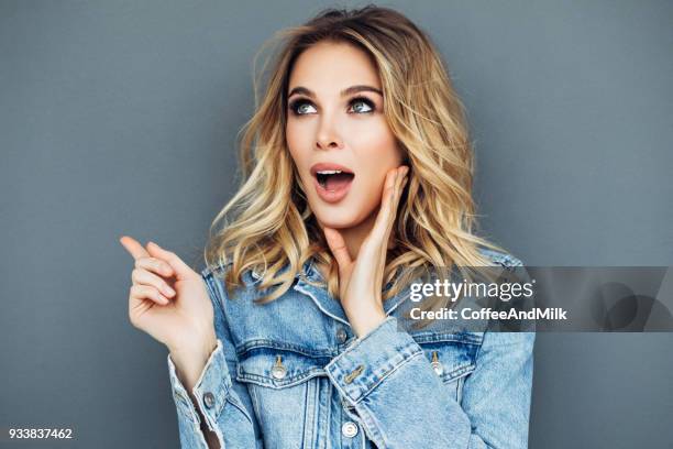 beautiful girl is pointing at something with her finger - beautiful woman shocked stock pictures, royalty-free photos & images