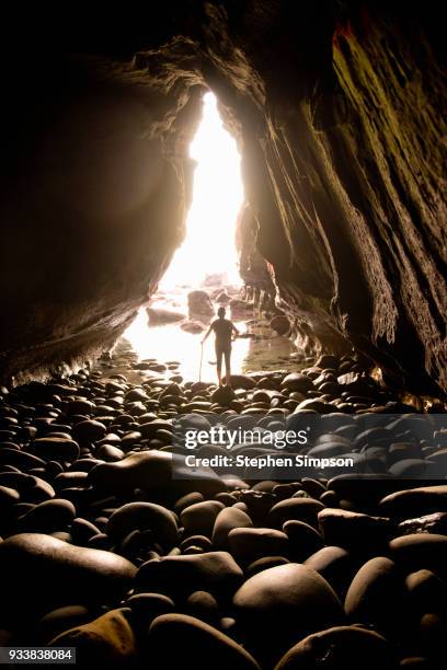 mature woman looking at sea through cave opening at low tide - la jolla stock-fotos und bilder