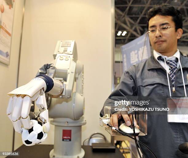 Japan's robot venture Squse employee operates a robot hand, powered by air pressure to picks up a soft ball for a demonstration at the International...