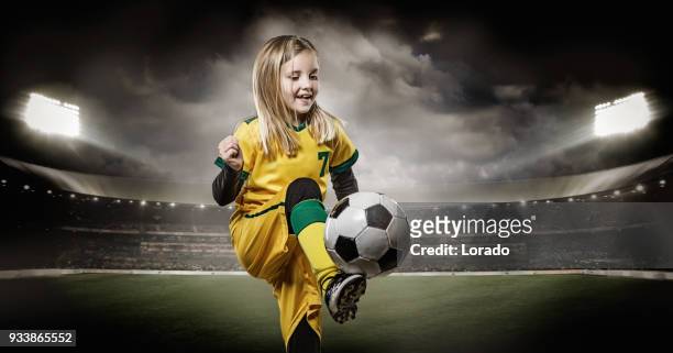jong meisje voetballer schoppen van een voetbal in een verlichte stadion - verdediger voetballer stockfoto's en -beelden