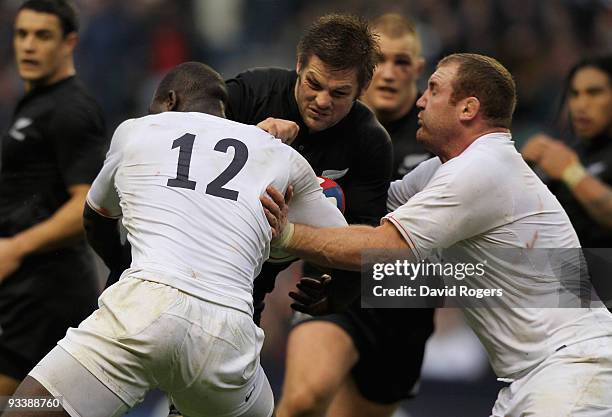 Richie McCaw of New Zealand is tackled by Ayoola Erinle and Tim Payne of England during the Investec Challenge Series match between England and New...