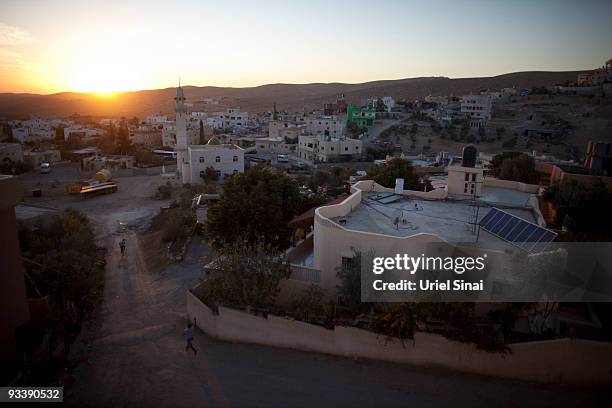 Photovoltaic solar panels dominate the rooftops as the setting sun casts its glow on November 23, 2009 over the Bedouin Arab village of Darajat in...