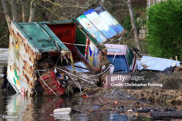 Car and a transport container lie in the garden of a home in the wake of last weeks devastating floods in Cumbria on November 25, 2009 in...