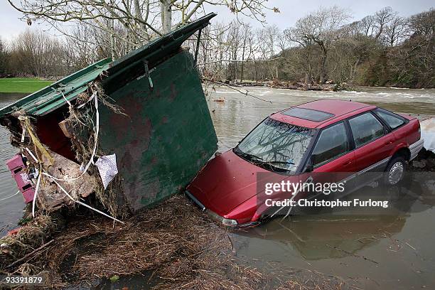 Car and a transport container lie in the garden of a home in the wake of last weeks devastating floods in Cumbria on November 25, 2009 in...