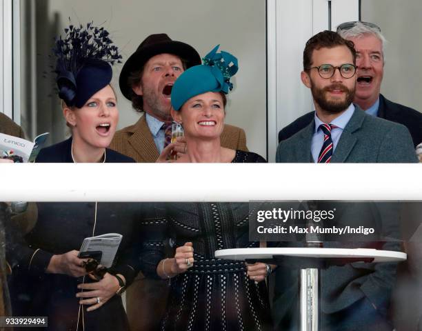 Zara Phillips, Dolly Maude and Jamie Dornan watch the racing as they attend day 4 'Gold Cup Day' of the Cheltenham Festival at Cheltenham Racecourse...