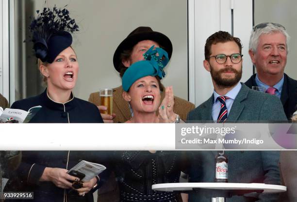 Zara Phillips, Dolly Maude and Jamie Dornan watch the racing as they attend day 4 'Gold Cup Day' of the Cheltenham Festival at Cheltenham Racecourse...