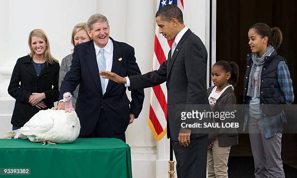President Barack Obama waves his hand as he pardons a turkey named Courage, alongside his daughters Malia and Sasha , and National Turkey Federation...
