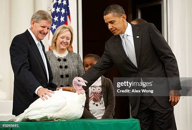 President Barack Obama pats a turkey named "Courage" as daughter Sasha looks on during an event to pardon the 20-week-old and 45-pound turkey at the...