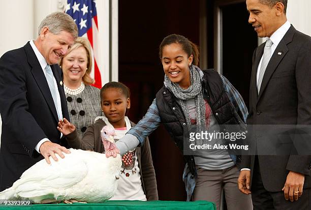 Malia Obama , daughter of U.S. President Barack Obama , pats a turkey named "Courage" as her sister Sasha and Walter Pelletier , Chairman of the...