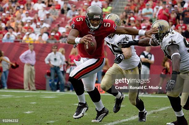 Quarterback Josh Freeman of the Tampa Bay Buccaneers scrambles and is chased by Scott Fujita and Charles Grant of the New Orleans Saints during a NFL...