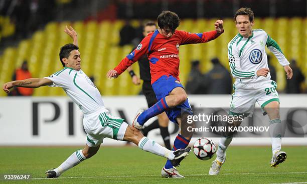 Moscow's Alan Dzagoev vies with WfL Wolfsburg's Brazilian midfielder Josue and German defender Sascha Riether during their UEFA Champions League...