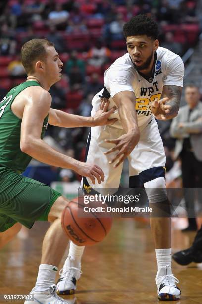 Esa Ahmad of the West Virginia Mountaineers passes against Jon Elmore of the Marshall Thundering Herd in the second half during the second round of...