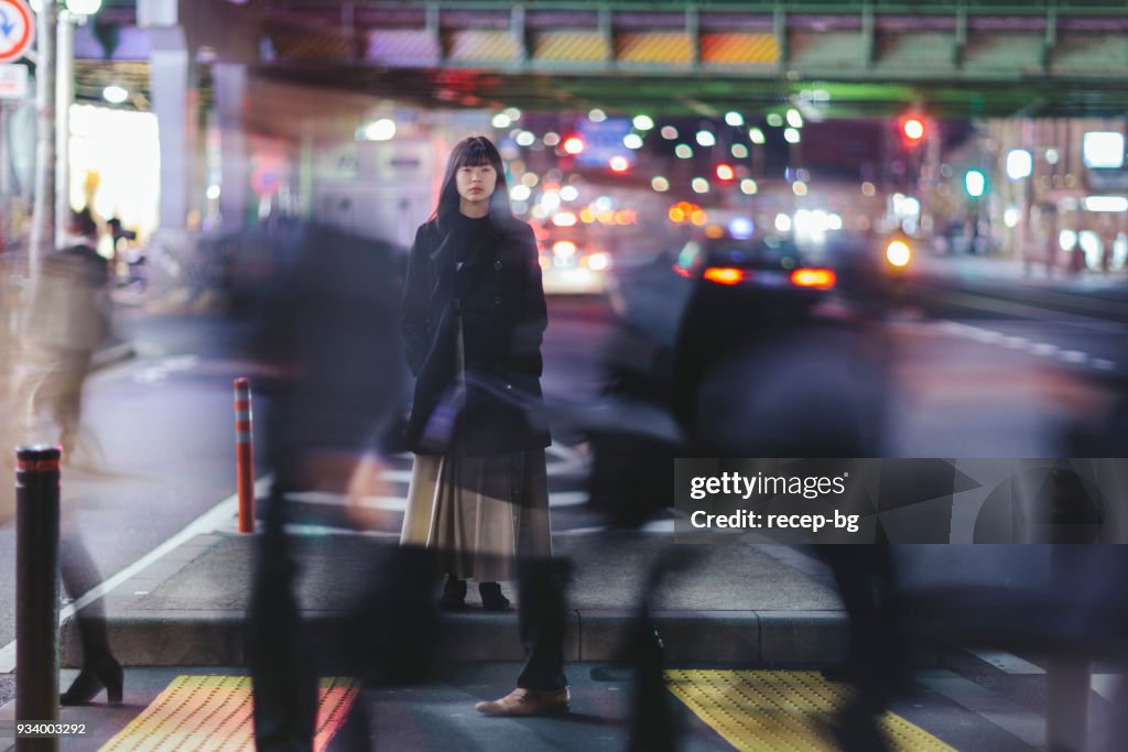 Femme debout dans la rue pendant la nuit à Tokyo