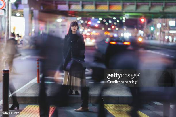 woman standing in the street at night in tokyo - tokyo night stock pictures, royalty-free photos & images