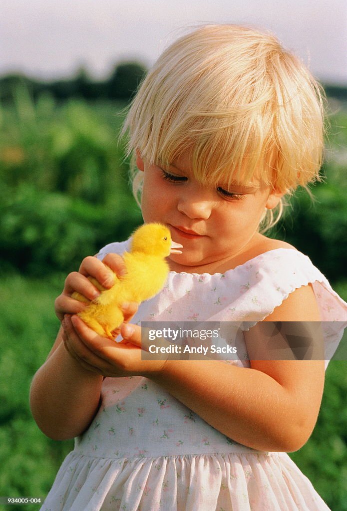 Girl (2-4) holding duckling in hand