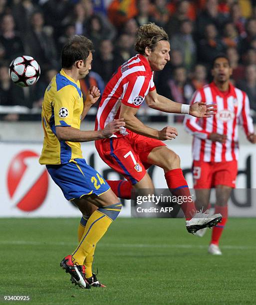 Atletico Madrid's Diego Forlan jumps as he battles with Apoel Nicosia's Christos Kontis during their UEFA Champions League group D football match at...