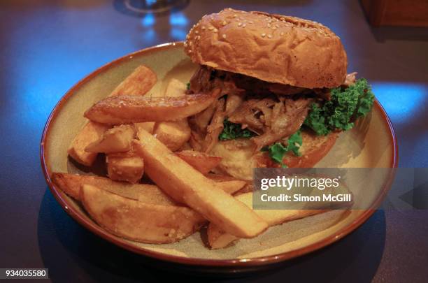 pulled lamb burger on a sesame seed bun and served with potato chips - kale chips stock pictures, royalty-free photos & images