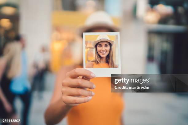 frau zeigt sofortbild zur kamera - passfoto stock-fotos und bilder