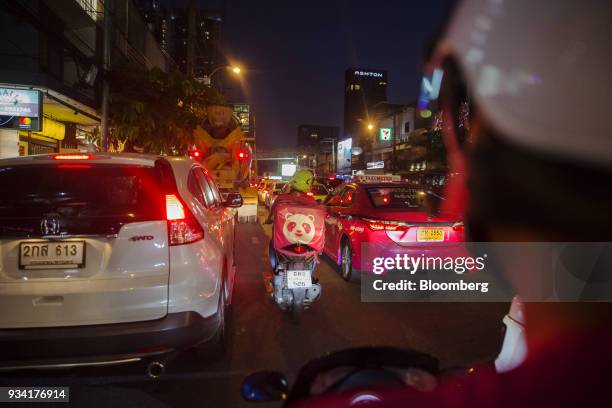 Couriers for Foodpanda, a meal-delivery service operated by Delivery Hero AG, make their way through traffic at night in Bangkok, Thailand, on...