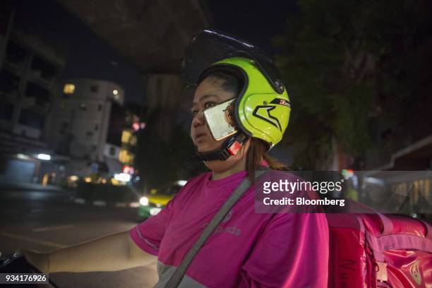 Courier for Foodpanda, a meal-delivery service operated by Delivery Hero AG, has her smartphone tucked in the side of her helmet while riding her...