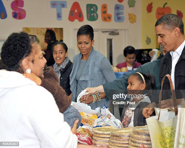 Malia Obama, first lady Michelle Obama, Sasha Obama and U.S. President Barack Obama hand out food at Martha's Table November 25, 2009 in Washington,...