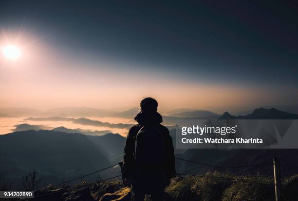 silhouette man at peak of mountains - bergsteiger gipfel stock-fotos und bilder