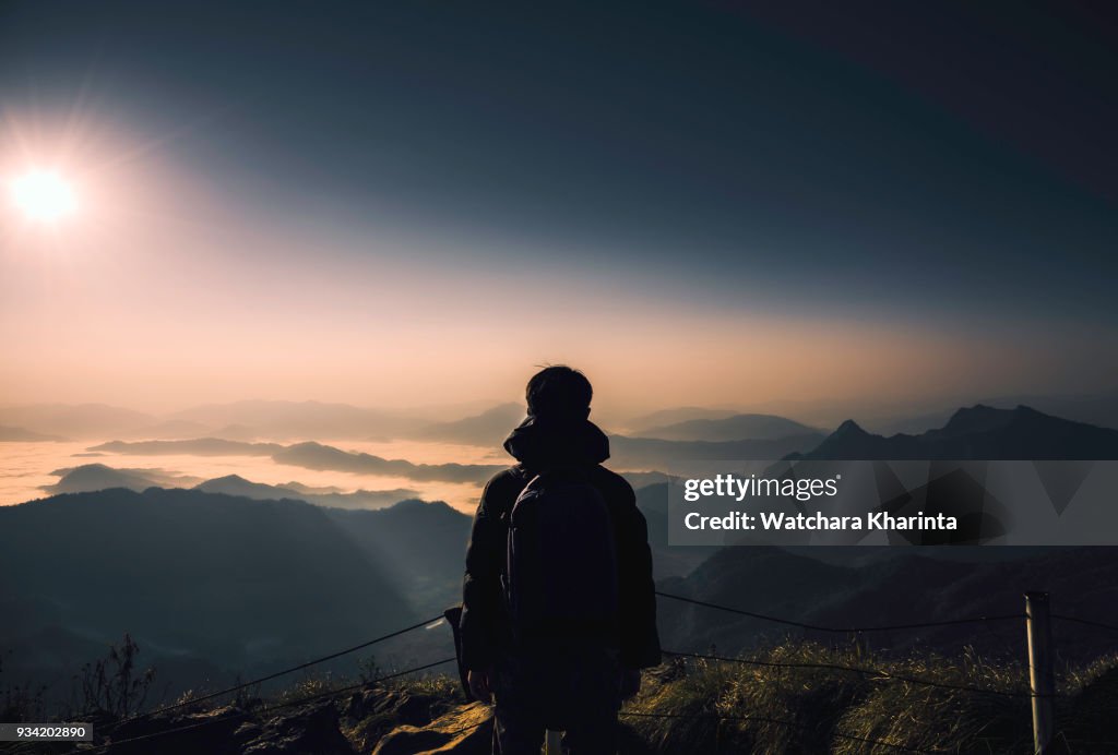 Silhouette man at peak of mountains