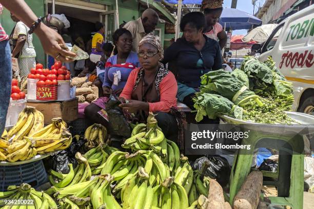 Customer passes a Ghana cedi banknote to a street vendor for the purchase of fresh produce in Accra, Ghana, on Thursday, March 15, 2018. Ghana wants...