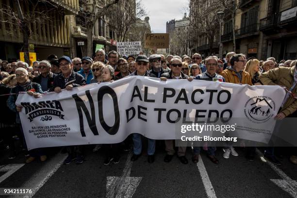 Protesters walk with a banner along Roger de Lluria street during the 'Marea Pensionista' demonstration for pension reform in Barcelona, Spain, on...