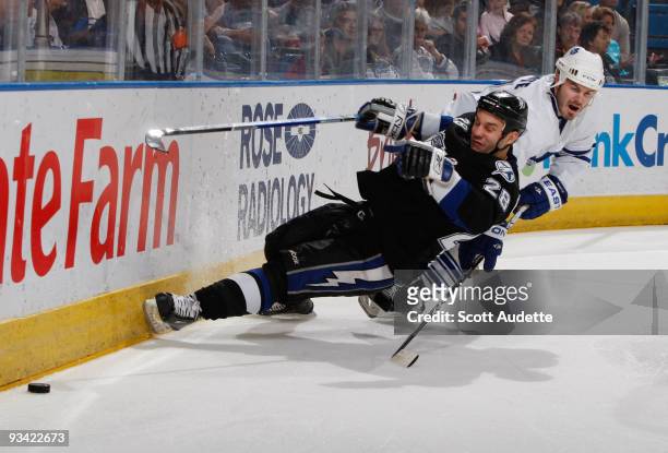 Ian White of the Toronto Maple Leafs prevents Zenon Konopka of the Tampa Bay Lightning from getting to the puck along the boards during the first...