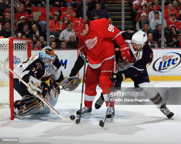 Tomas Holmstrom of the Detroit Red Wings and Ron Hainsey of the Atlanta Thrashers battle for the loose puck as teammate Ondrej Pavelec gets into...