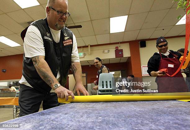 Members of the Hells Angels motorcycle tape plastic table cloths to tables in preparation for Thanksgiving dinner at the St. Anthony Foundation...