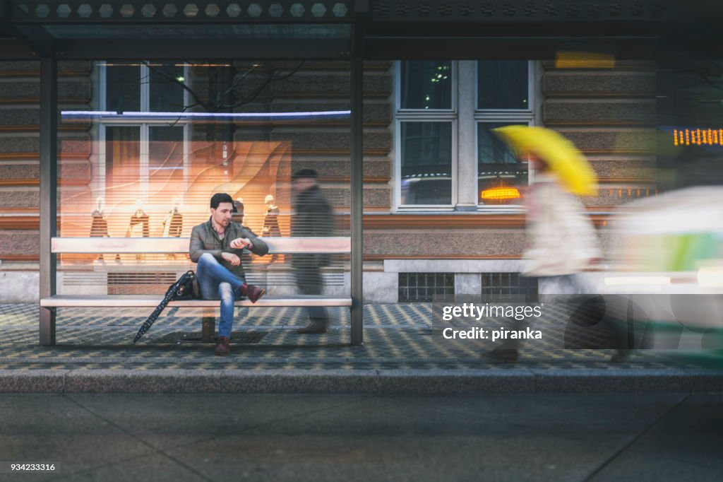 Man on the bus stop on a rainy night