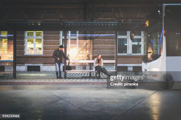 people on the bus stop on a rainy night - waiting stock pictures, royalty-free photos & images