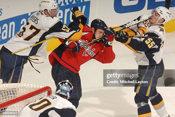 Tyler Myers and Joshen Hecht of the Buffalo Sabres put a hit on Chris Clark of the Washington Capitals during a NHL hockey game on November 25, 2009...