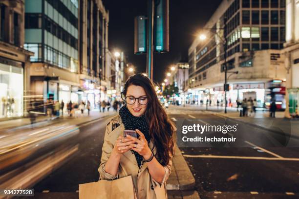 young woman on the streets of london downtown in the evening calling a cab - downtown shopping stock pictures, royalty-free photos & images