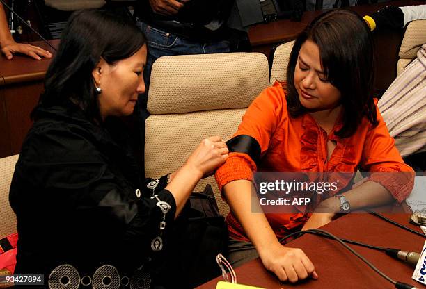Journalist ties a black armband onto the arm of a colleague during a press conference in Quezon City, a suburb of Manila, on November 26 to show that...