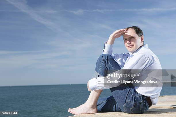 man sitting on beach - shielding eyes stock pictures, royalty-free photos & images