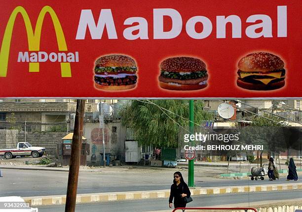 Iraqi Kurd woman passes under a giant billboard of a fast-food restaurant in the Iraqi Kurdish city of Suleimaniya, some 340 kms north-east of...