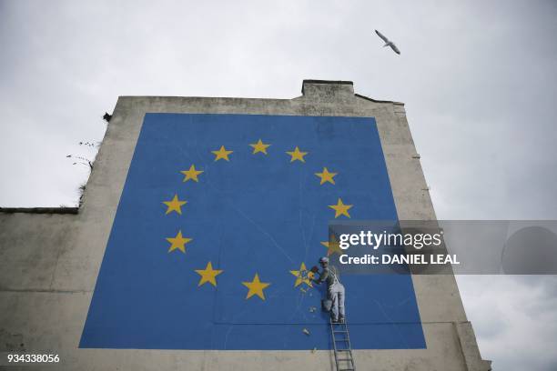 Mural by British artist Banksy, depicting a workman chipping away at one of the stars on a European Union themed flag, is pictured in Dover, south...