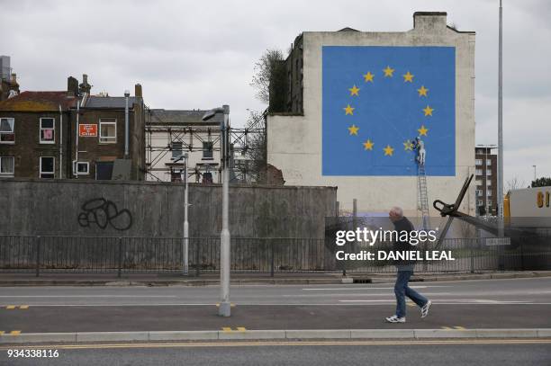 Mural by British artist Banksy, depicting a workman chipping away at one of the stars on a European Union themed flag, is pictured in Dover, south...